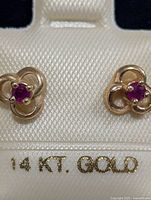 Front view of ruby stud earrings in display card showing 14 KT. GOLD stamp