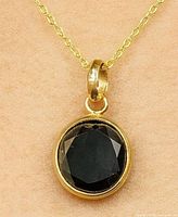 Pendant on chain showing front view of black diamond in yellow gold bezel