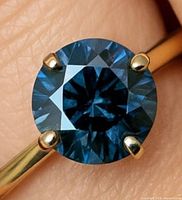 Close-up of the blue diamond in prong setting on gold band