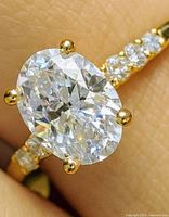 Close view of oval lab diamond in four-prong setting with accent stones