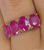 Ring on finger showing four of the rubies and gold prong setting
