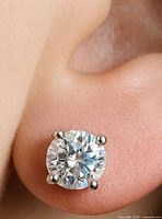 Close-up of one diamond stud earring in ear showing four-prong 14K setting and round brilliant stone