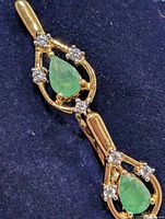 Front view showing both earrings with emerald and accent stones
