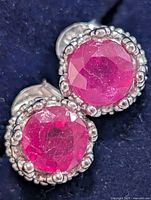 Front view of both ruby stud earrings showing faceted stones and silver crown setting