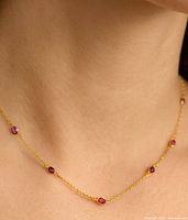 Necklace worn on model neck showing ruby stations and chain style