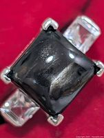 Front view of ring showing central black gemstone and clear side stones
