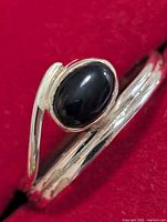 Close view of oval black onyx cabochon set in silver bypass ring