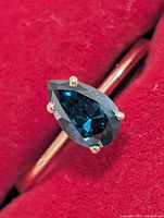 Front view showing pear-shaped blue gemstone in prong setting
