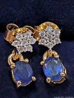 Close-up of both earrings showing sapphire stones and starburst clusters