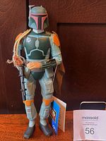 Front view of Boba Fett figure with tag, blaster, cape and braids visible