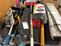Assorted car accessories piled together showing brushes, floormats, boxed tire inflator and power cleaner