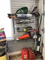 Shelf area showing seed spreader on top shelf, gas cans and traffic cone below