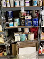 Full view of grey metal shelving loaded with paint cans