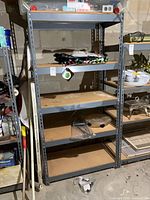 Full view of shelving unit showing five particleboard shelves within grey metal frame