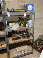 Front view of grey metal shelving unit showing four particle board shelves, contents on shelves not included