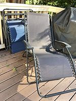 Two foldable zero gravity lounge chairs, black and navy, on deck