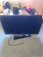 Front view of Samsung TV with remote and power cord