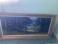 Full view of framed landscape painting leaning against wall