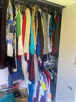 Closet view upper and lower racks filled with assorted women’s tops and outerwear on hangers