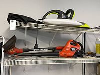 Garden Groom trimmer with bag on upper shelf, Black & Decker Grass Hog trimmer with charger on lower shelf