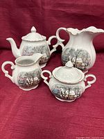 Front view of all four porcelain tea service pieces showing Winter Village design and gold trim
