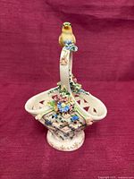 Front view of porcelain lattice basket with bird handle and floral appliqués