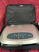 Bag open displaying padded interior with projector for scale