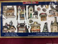 Front of boxed Holiday Time Village Collectibles 19-Piece Village Set showing contents through plastic window