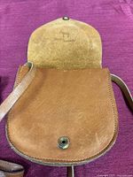 Open brown leather purse showing suede interior, snap button and stamped logo