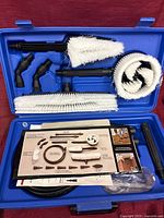 Open blue case showing brushes, adaptors, extensions, hose and fittings