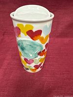 Side view of Starbucks ceramic travel mug showing multicolor hearts pattern and lid
