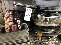 Stacked muffin trays, loaf pans, packaged cupcake plunger visible