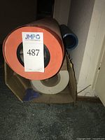 Front view of orange paper roll with blue plastic roll and clear roll in box