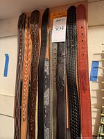 Front view showing majority of belts hanging on board, various colours and patterns