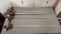 Four long bar clamps laid side by side