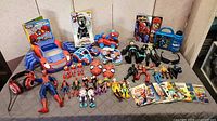 Full lot overview on table showing action figures, vehicles, masks, books, headphones