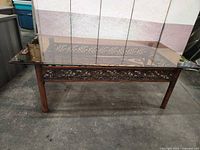 Full view of coffee table front showing glass top and decorative metal apron