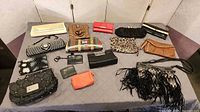 Overview of 14 handbags and clutches on table