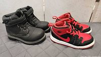 Two pairs toddler shoes side by side: Nike Jordan sneakers and black boots