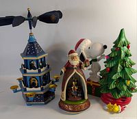 Overall view of all four Christmas décor items: wooden carousel, Santa figurine, Snoopy figure with tree, Woodstock star