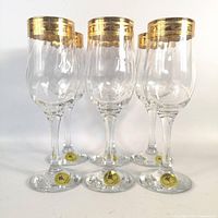 Full view of five glasses front, showing gold rims and labels on bases