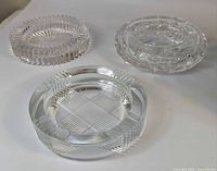 Three clear crystal glass ashtrays showing top view and patterns