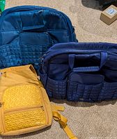 All three LUG bags: two blue totes, one yellow backpack