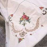 Close view of embroidered rose bouquet and crochet edging on tablecloth