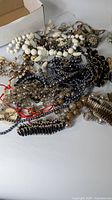 Pile of assorted necklaces, beads and chains on table