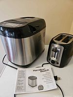 Breadmaker, toaster and manual on table