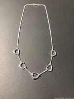 Full view of silver-tone necklace showing five heart links