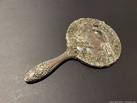 Front view showing ornate metal handle and shattered mirror glass