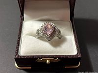 Ring in open display case showing pink center stone and halo