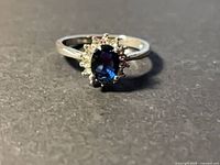 Front view of sterling silver ring showing oval blue stone and halo of clear stones